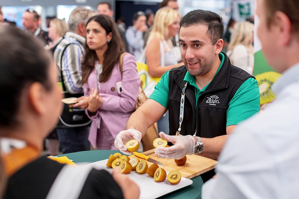 man cutting and serving a yellow kiwi