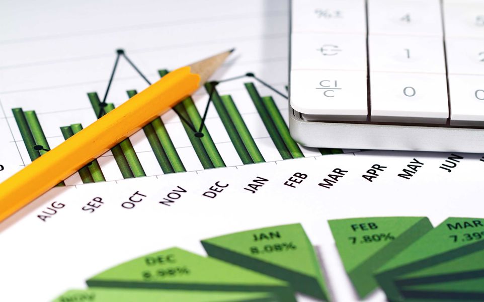 A yellow pencil and calculator sitting on top of a print out of a bar chart and pie chart displaying data by month.